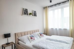 a bedroom with a bed with white sheets and a window at Apartament 2 Komfort in Słupsk