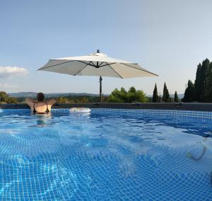 een vrouw zittend in een zwembad met een paraplu bij Villa Cicogna, Private villa with exclusive use pool in Terranuova Bracciolini