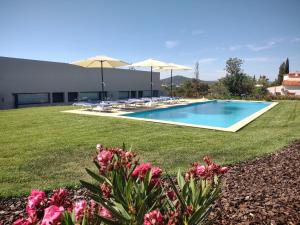 einen Pool im Garten mit Sonnenschirmen und Blumen in der Unterkunft Suites Sunny hill in Moncarapacho