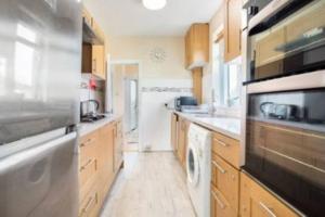 a large kitchen with wooden cabinets and a dishwasher at Wembley 2 Bed/2 Bath Modern Apt in London