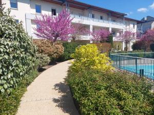 una passerella di fronte a un edificio con fiori viola di Appartement 65 m² avec piscine. a Tours
