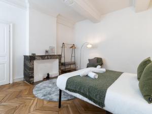 a white bedroom with a bed and a fireplace at La petite escapade - Vienna Authentica in Vienne