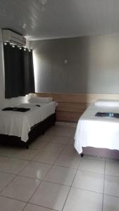 a bedroom with two beds and a tiled floor at Hotel Copacabana in Araucária