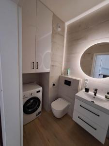 a white bathroom with a toilet and a sink at Apartament Długa Uniejów in Uniejow