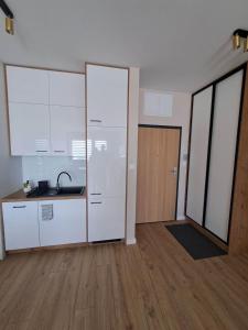 an empty kitchen with white cabinets and a wooden floor at Apartament Długa Uniejów in Uniejow