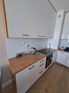 a kitchen with white cabinets and a wooden counter top at Apartament Długa Uniejów in Uniejow