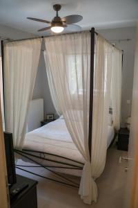 a bed with white curtains and a ceiling fan at Zak's House in Platamonas