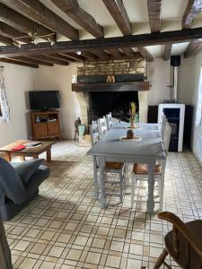 a table and chairs in a living room with a fireplace at Domaine de l’épinerie Le fournil in Omméel