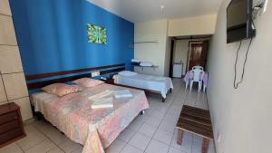 a hotel room with two beds and a tv at Hotur Hotel in Guarapari