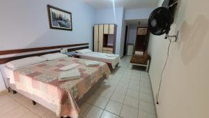 a hotel room with two beds and a fan at Hotur Hotel in Guarapari