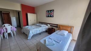 a hotel room with two beds and a table and chairs at Hotur Hotel in Guarapari