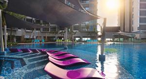 uma piscina com espreguiçadeiras roxas num edifício em Atlantis Residences By 360 HOME em Malaca