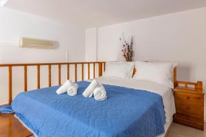 1 dormitorio con cama azul y almohadas blancas en Joanna Apartments, en Agia Pelagia