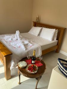 Una cama con una mesa con una botella de vino y un plato de fruta. en Daria, 