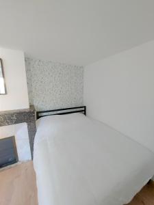 a white bed in a room next to a wall at ° Appart 3 - Lunéville centre ° in Lunéville