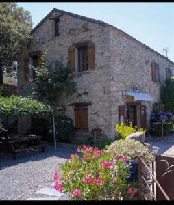 uma velha casa de pedra com flores em frente em U Granu di Bellezza em Casta