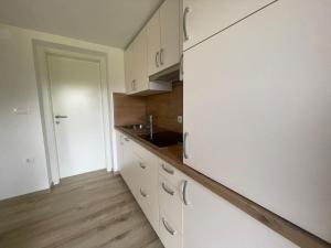 a kitchen with white cabinets and a wooden floor at The Boathouse Apartment in Bled