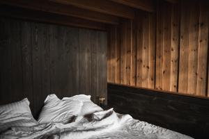 uma cama não feita num quarto com paredes de madeira em La Grenouillère em Montreuil-sur-Mer