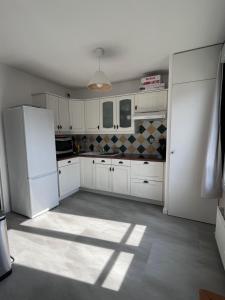 a kitchen with white cabinets and a white refrigerator at Appartement Le Rochettois - VALGELON LA ROCHETTE - 25 mn station de ski Collet d'Allevard in La Rochette