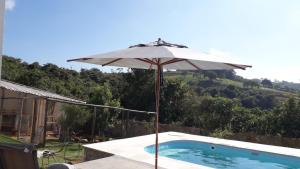 ein weißer Regenschirm neben einem Pool in der Unterkunft Guest House em Tiradentes MG in Tiradentes