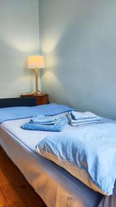 a bedroom with a bed with blue sheets and a lamp at Yellow and blue relax house in Piraeus