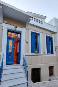 a house with a blue and red door and stairs at Yellow and blue relax house in Piraeus