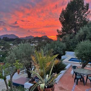 a sunset over a garden with a table and chairs at Villa Rios in Xàtiva