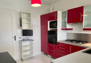 a kitchen with red cabinets and a tv in it at Rez de jardin de 65m2 dans villa à Nice in Nice +11 photos