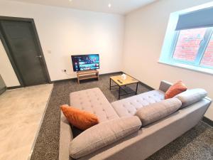Homestay by BIC Oates 8 في دوزبري: غرفة معيشة مع أريكة وتلفزيون بشاشة مسطحة