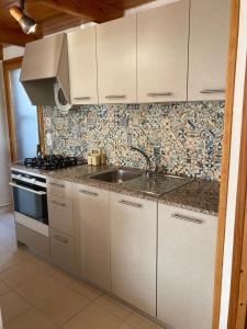 una cocina con armarios blancos y fregadero en Casa Gonia, en Riumar