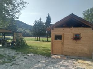ein kleines Holzgebäude mit einer Tür im Hof in der Unterkunft Hiška Zeleni raj in Podnart