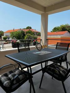 a black table and two chairs on a balcony with wine glasses at Holiday Home Bajlo in Zadar