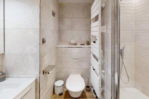 a white bathroom with a toilet and a shower at Accès direct plage et piscine - Entre mer et marais salants in Batz-sur-Mer