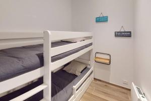 a bedroom with two bunk beds and a sign on the wall at Accès direct plage et piscine - Entre mer et marais salants in Batz-sur-Mer +1 photo