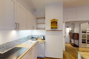 a kitchen with white cabinets and a sink at Accès direct plage et piscine - Entre mer et marais salants in Batz-sur-Mer