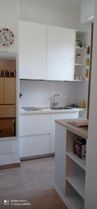 a white kitchen with white cabinets and a sink at Sa Frummiga in Cagliari