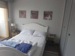 un letto bianco con due cuscini sopra in una camera da letto di FORT MAHON superbe appartement face mer a Fort-Mahon-Plage