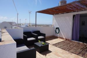 een patio met 2 stoelen en een tafel op een dak bij IMPLUVIUM Conil-Terraza Privada-Parking- mayores de 25 años in Conil de la Frontera