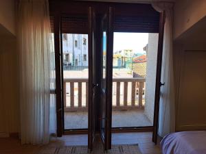 eine offene Glasschiebetür zu einem Balkon mit einem Bett in der Unterkunft Casa privada centrica in Vilanova de Arousa
