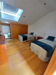 two beds in a room with a skylight at A de Bego in Mougás