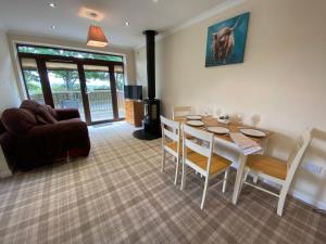 een woonkamer met een tafel en stoelen en een bank bij The Lodge at Woodend in Kemnay