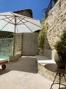 eine Terrasse mit einem Tisch und einem Sonnenschirm in der Unterkunft Les Vieux Murs in Montfort