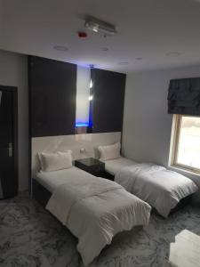 - une chambre avec 2 lits et une lumière bleue dans l'établissement Marina H, à Sohar