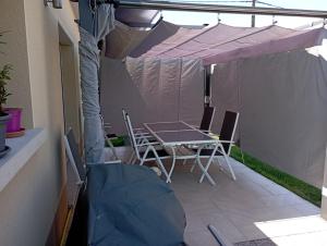 un patio con tavolo e sedie sotto una tenda. di LE JOLICY a Nexon