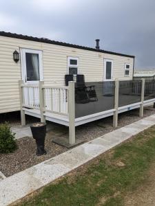a house with a deck with two chairs on it at E16 Millfields 6 berth caravan MAX 4 ADULTS Bob family's only and lead person must be over 30 in Ingoldmells