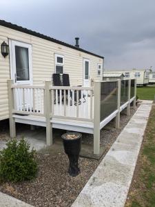 a house with a porch and a deck with chairs at Millfields 6 berth caravan MAX 4 ADULTS Bob family's only and lead person must be over 30 in Ingoldmells