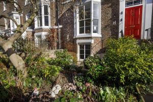 a red door on a brick house with flowers at The Garden Square - Unique luxury apartment in historic garden square - for up to 4 people in York