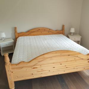 Iveland的住宿－Gårdshuset Håverstad，卧室内的木床,带2个床头柜