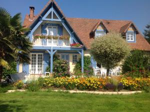 a house with a flower garden in front of it at La Maison Bleue Normande in Maniquerville