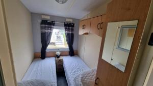 a small room with two beds and a window at Millfields 6 berth caravan MAX 4 ADULTS Bob family's only and lead person must be over 30 in Ingoldmells